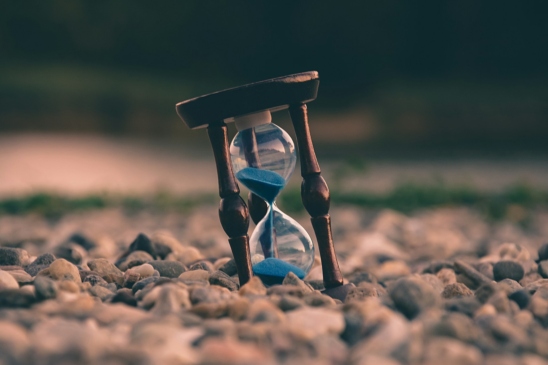 Eine Sanduhr steht auf einem verlassenen Steinstrand